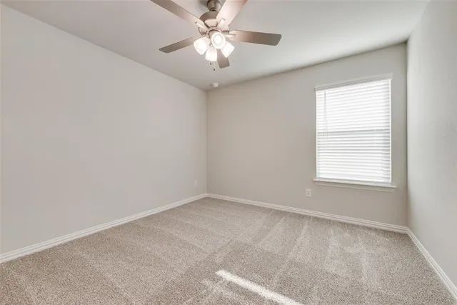 an empty room with a window and a fan