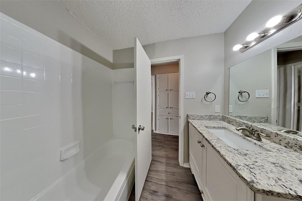6421 Old Mill Circle Watauga, TX 76148 - Photo 16 of 18 a bathroom with a granite countertop sink a mirror and a bathtub