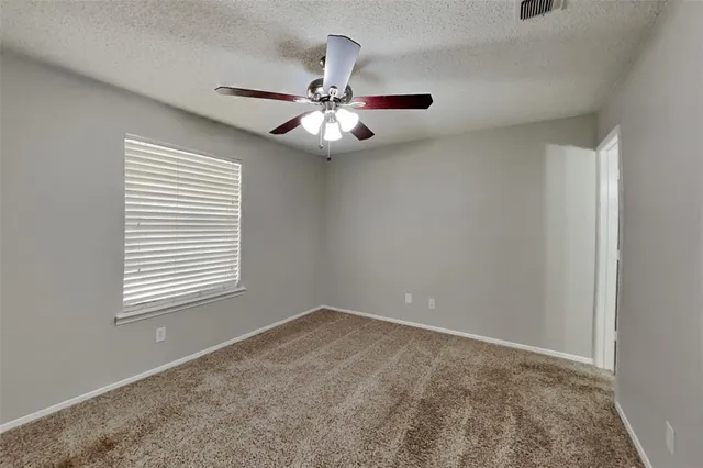 an empty room with windows and fan