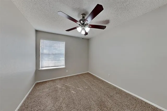 an empty room with window and ceiling fan