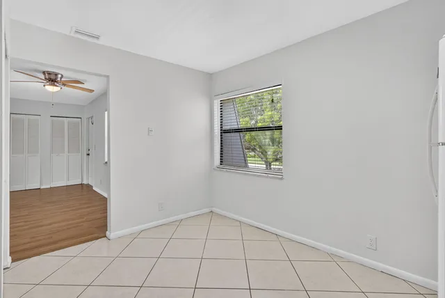 a view of an empty room with window and chandelier fan