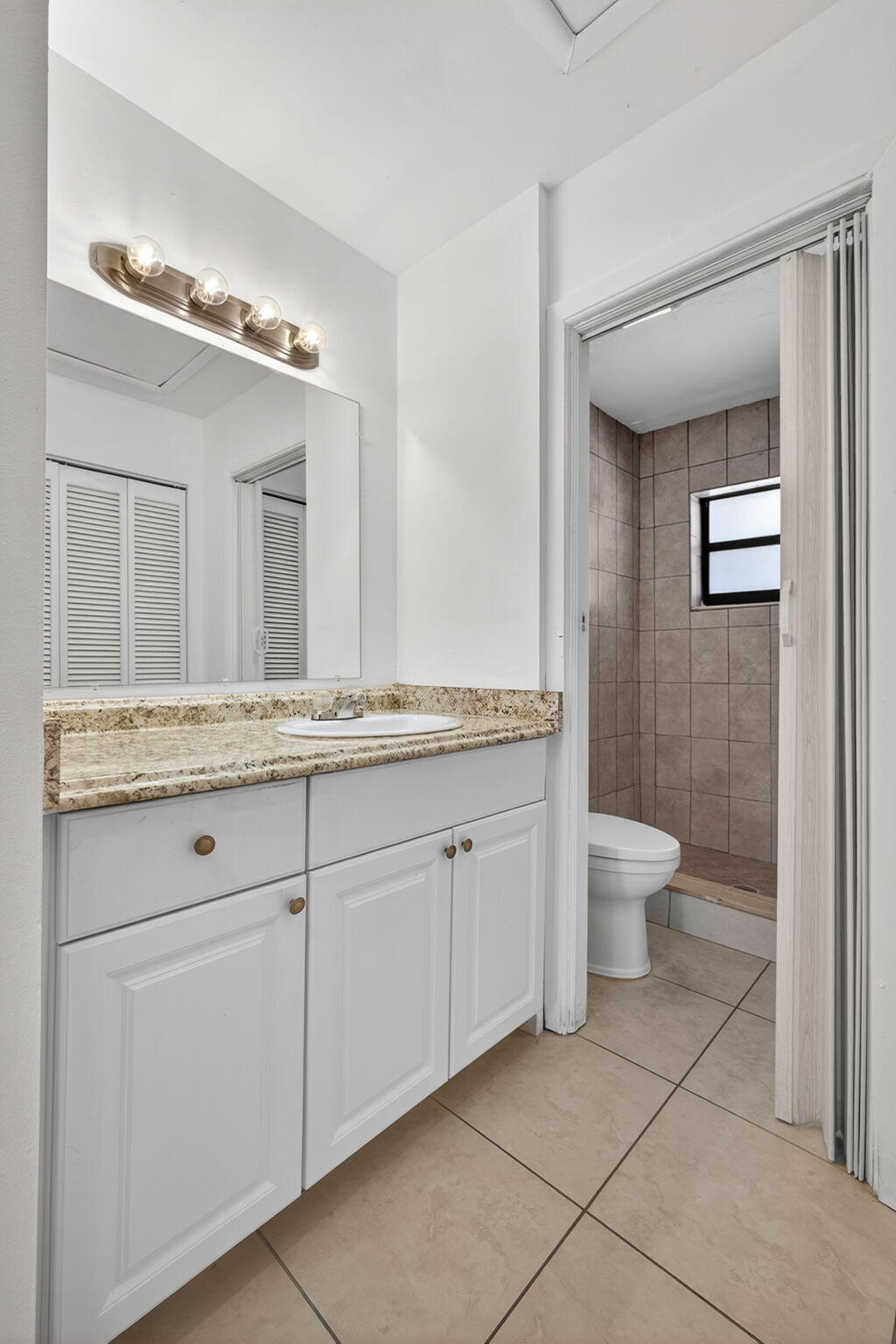 1580 Montauk Drive, Unit 1582 Wellington, FL 33414 - Photo 22 of 28 a bathroom with a granite countertop sink a toilet and a mirror