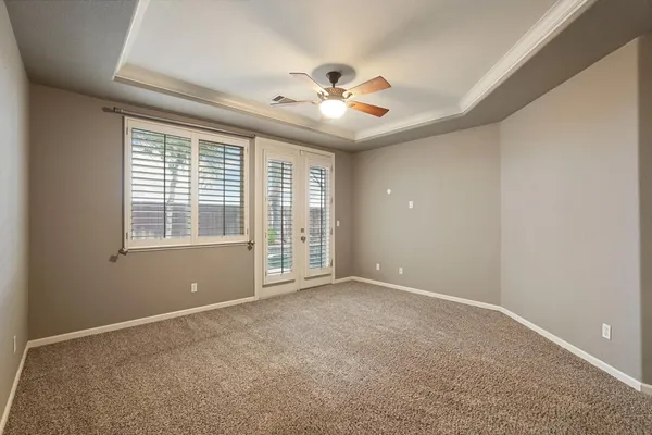 an empty room with windows and ceiling fan