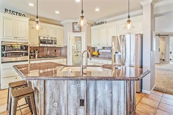 a kitchen with stainless steel appliances kitchen island granite countertop a refrigerator a stove and a sink with wooden floor