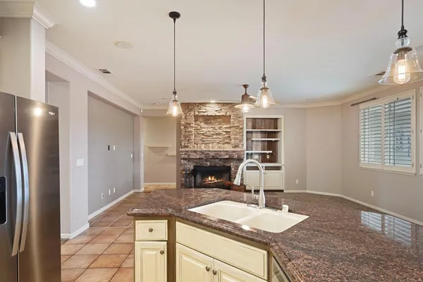 a kitchen with kitchen island granite countertop a refrigerator a stove and a sink with wooden floor