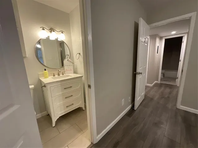 a view of a dresser mirror and bedroom with wooden floor