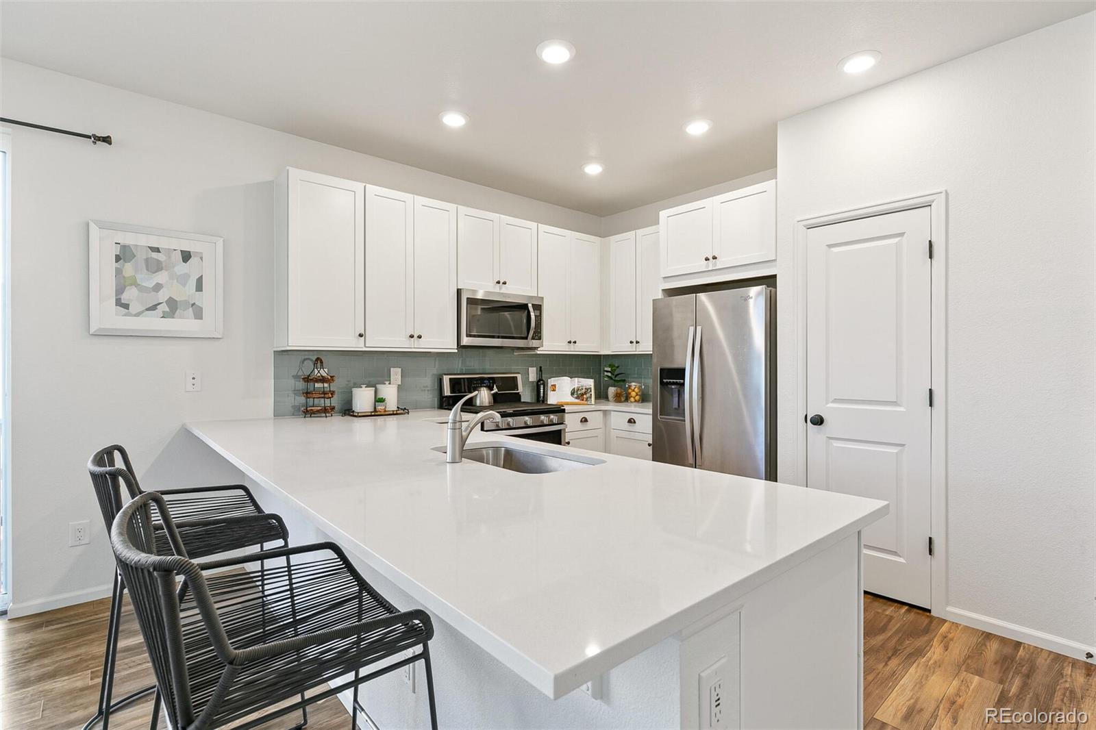 11159 East 25th Drive Aurora, CO 80010 - Photo 9 of 23 a kitchen with stainless steel appliances a stove a refrigerator a sink a oven with white cabinets and wooden floor