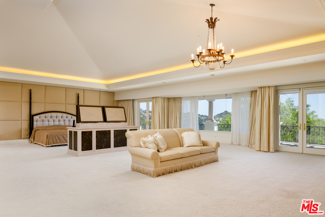 73 Beverly Park Lane Beverly Hills, CA 90210 - Photo 18 of 24 a spacious bedroom with a large bed and a chandelier