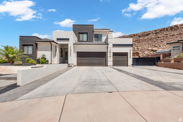 6105 Bunda Way St. George, UT 84790 - Photo 2 of 49 Modern architectural residence with a white stucco facade and dark horizontal siding accents