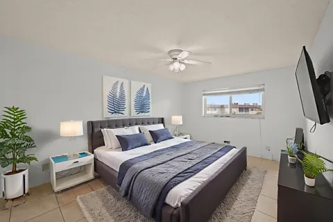 a bedroom with a bed potted plant on the dresser and a window