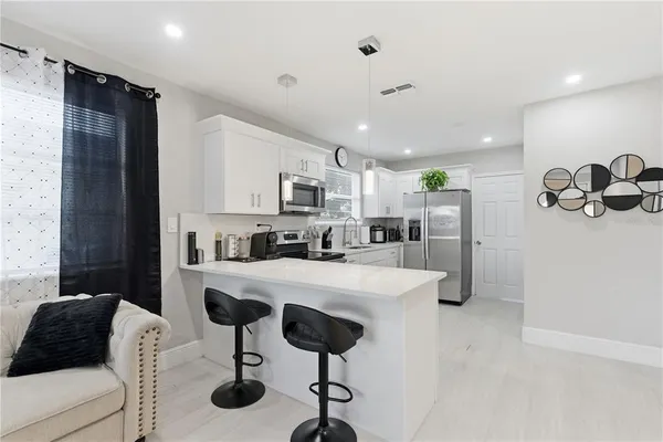 a kitchen with stainless steel appliances kitchen island granite countertop a refrigerator a stove a sink dishwasher with a dining table and chairs