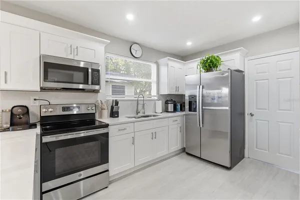 a kitchen with granite countertop a refrigerator stove and microwave