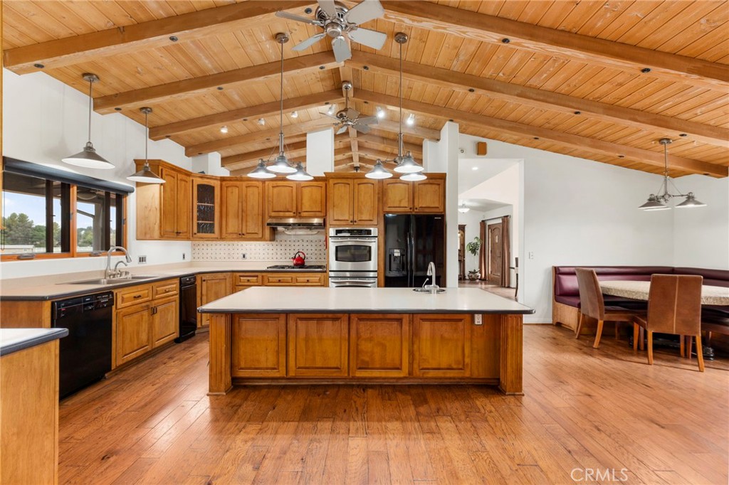43991 John Warner Road Temecula, CA 92592 - Photo 13 of 39 a large white kitchen with a large island a stove a sink a dining table and chairs with wooden floor