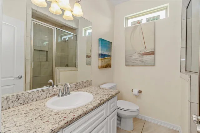 a bathroom with a granite countertop sink mirror vanity and toilet