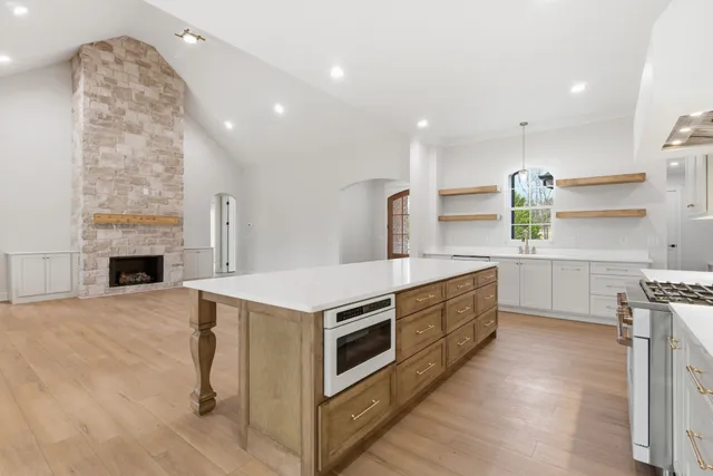 a kitchen with stainless steel appliances kitchen island wooden cabinets and a fireplace