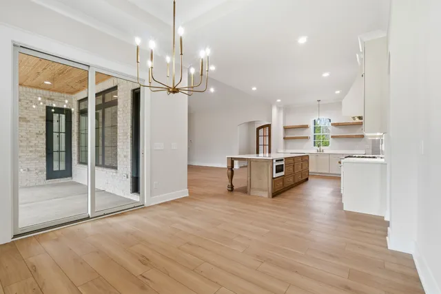 a living room with stainless steel appliances kitchen island granite countertop a refrigerator a stove and a sink with wooden floor