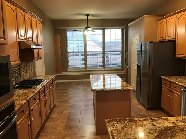 a kitchen with stainless steel appliances granite countertop a refrigerator a stove and a sink