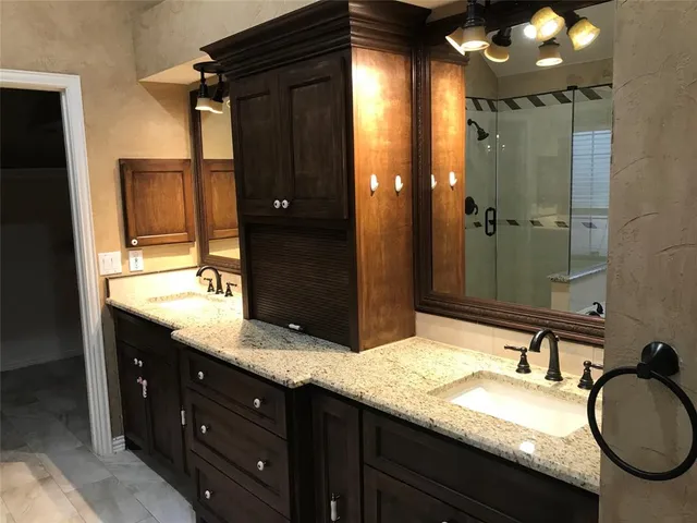 a bathroom with a granite countertop double vanity sink and a mirror