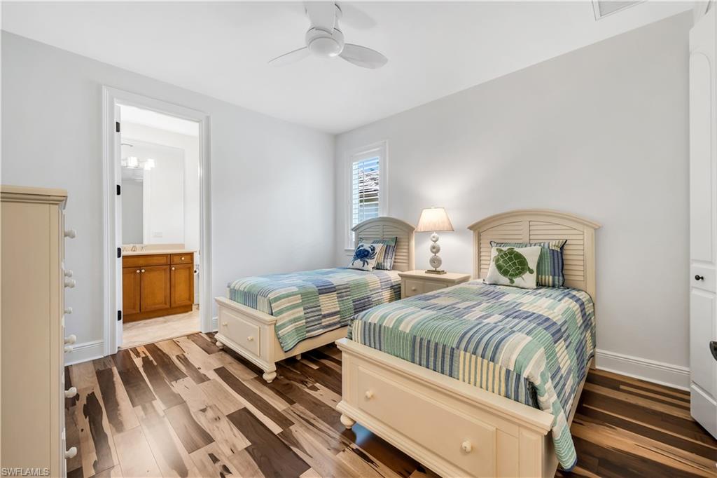 11875 Hedgestone Court Naples, FL 34120 - Photo 17 of 29 Wood-finish flooring, ceiling fan, white window shutters, and an attached bathroom with a single vanity and wall-mounted lighting