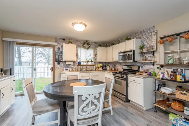 a kitchen with stainless steel appliances granite countertop a stove top oven a sink dishwasher and white cabinets with wooden floor