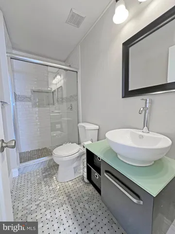 a bathroom with a sink a toilet a mirror and shower