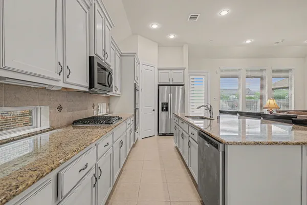 a kitchen with granite countertop a sink a counter top space stainless steel appliances and cabinets
