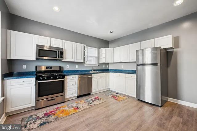 a kitchen with stainless steel appliances granite countertop a refrigerator oven a stove and a sink