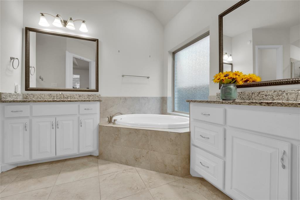 1011 Prairie Ridge Lane Arlington, TX 76005 - Photo 29 of 32 Bathroom featuring a built-in soaking tub, dual white vanities with granite countertops, large framed mirrors, and tile flooring