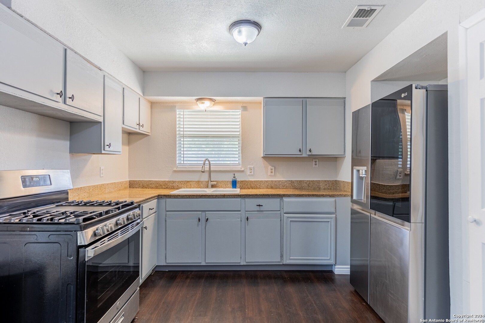 7802 Rimfire Drive San Antonio, TX 78227 - Photo 13 of 39 a kitchen with stainless steel appliances a sink cabinets and wooden floor