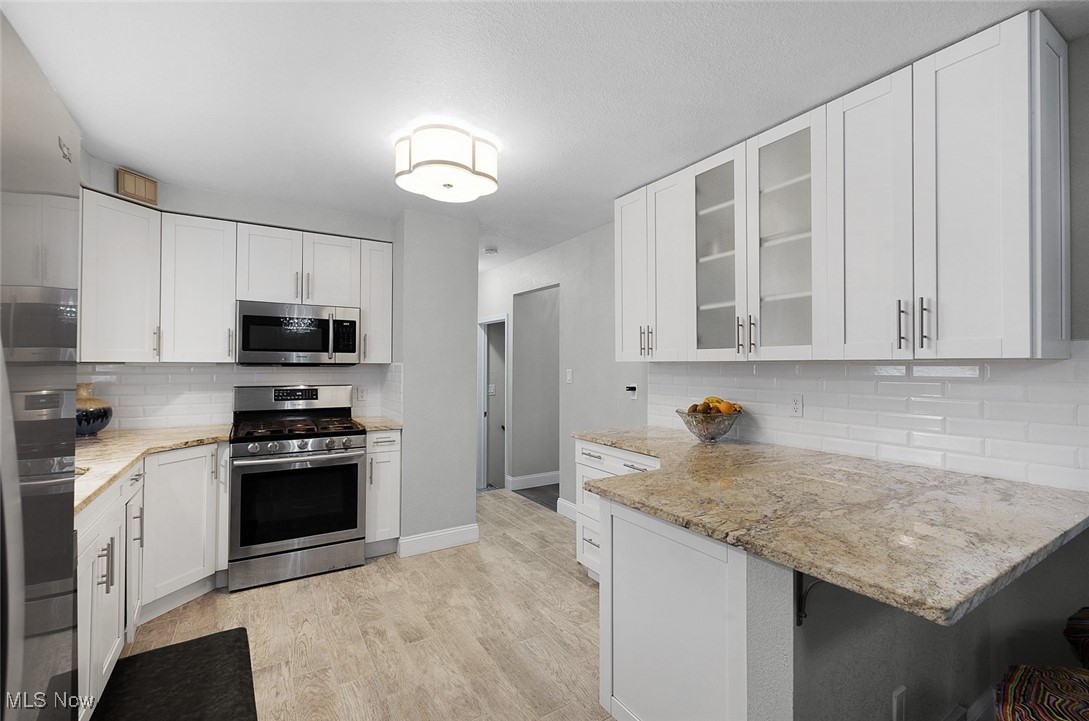 3913 Silsby Road Cleveland, OH 44118 - Photo 5 of 26 Kitchen with appliances with stainless steel finishes, backsplash, and white cabinetry