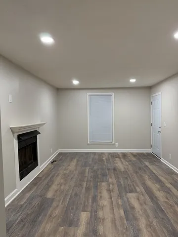 an empty room with wooden floor fireplace and windows