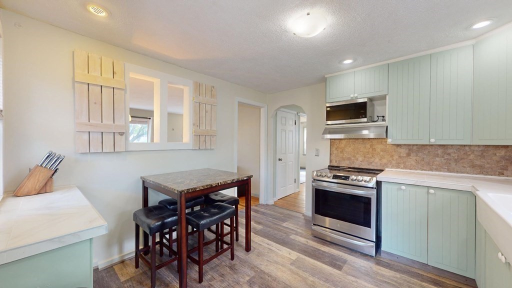 274 Cooper Street Springfield, MA 01108 - Photo 7 of 42 a kitchen with stainless steel appliances kitchen island granite countertop a stove a sink a refrigerator and a dining table with wooden cabinet