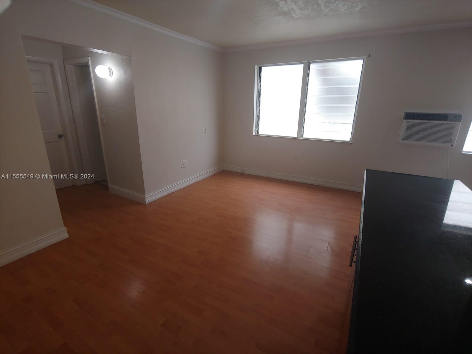 7928 Harding Avenue, Unit 8 Miami Beach, FL 33141 - Photo 27 of 30 a view of an empty room with wooden floor and a window