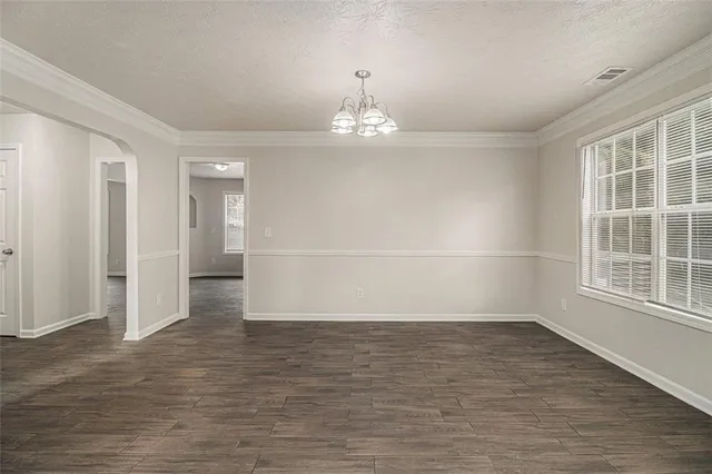 an empty room with wooden floor cabinet and windows