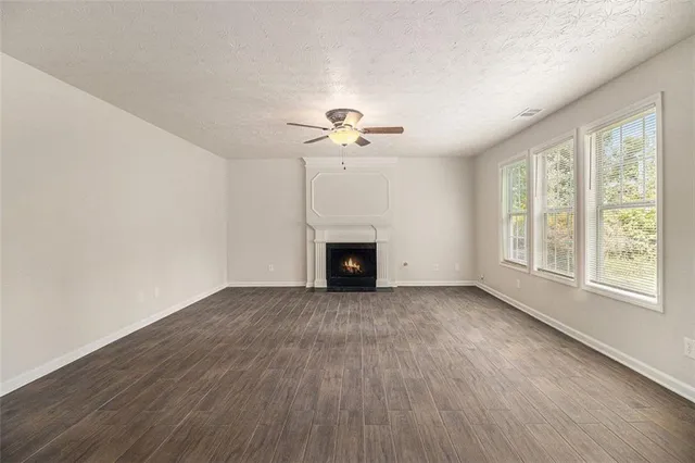 an empty room with chandelier fan and windows