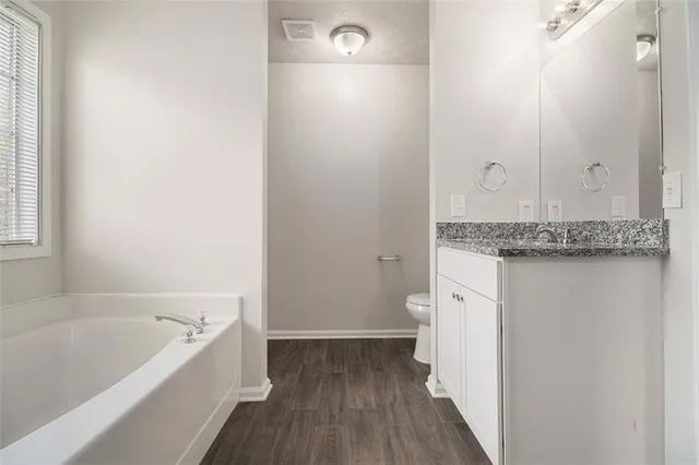 a bathroom with a granite countertop sink and a bathtub