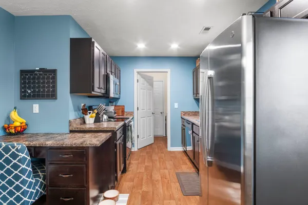 a kitchen with stainless steel appliances granite countertop a refrigerator a stove and a sink