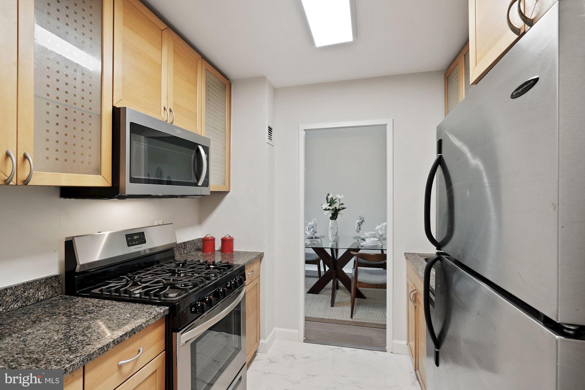 4000 Tunlaw Road Northwest, Unit 1123 Washington, DC 20007 - Photo 15 of 31 a kitchen with stainless steel appliances granite countertop a stove a sink dishwasher and a microwave oven with white cabinets