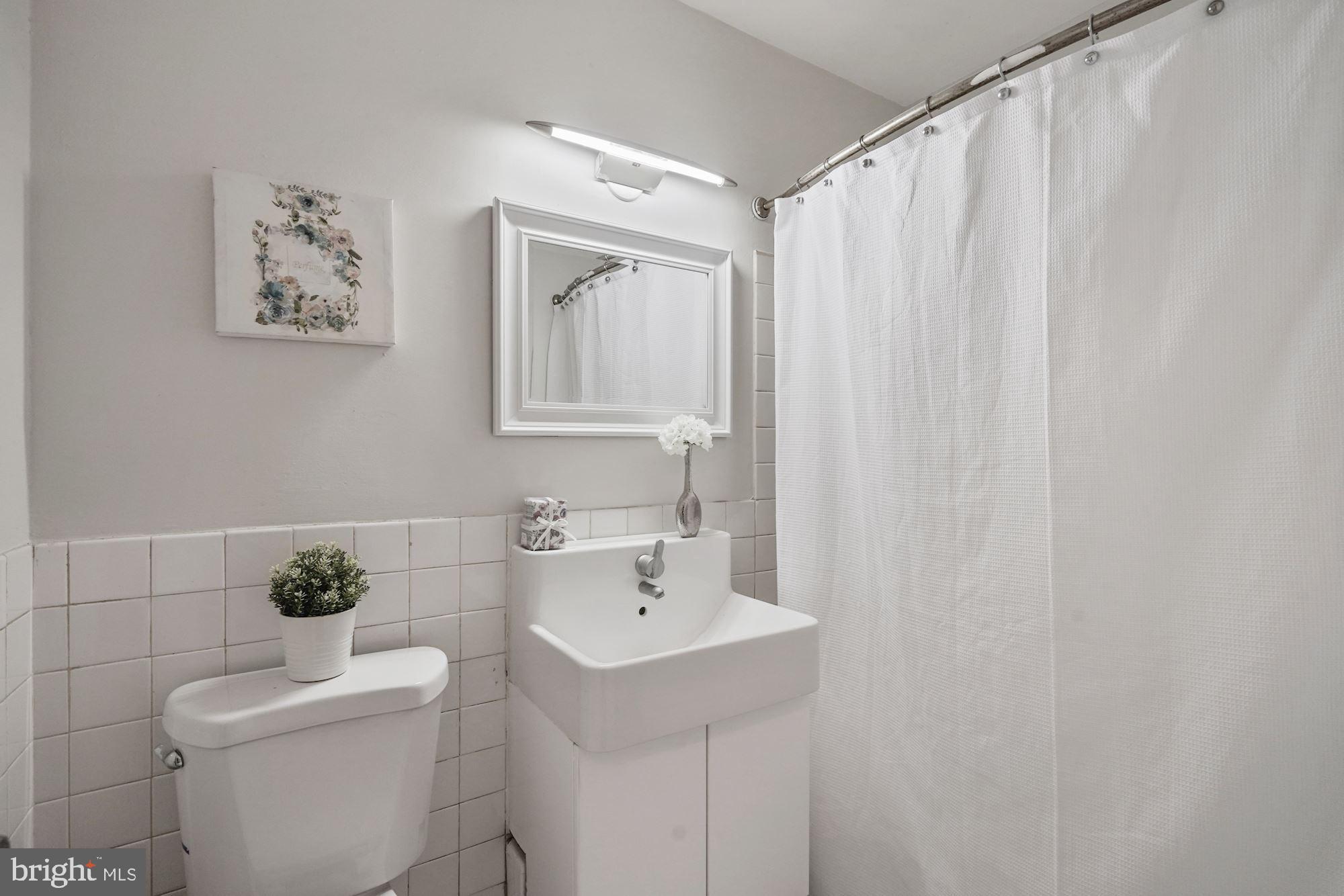 4000 Tunlaw Road Northwest, Unit 1123 Washington, DC 20007 - Photo 25 of 31 a bathroom with a sink a toilet and a mirror