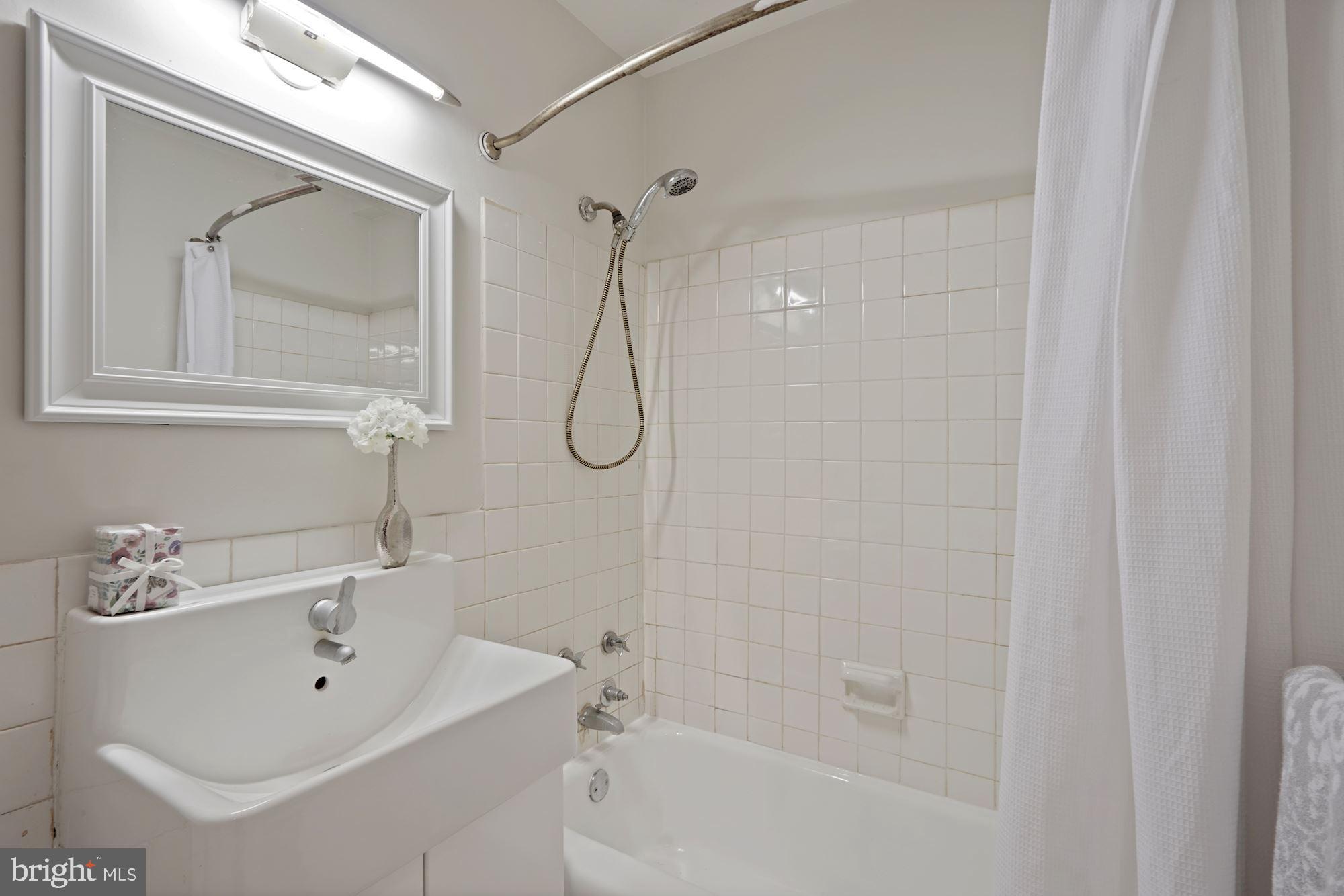4000 Tunlaw Road Northwest, Unit 1123 Washington, DC 20007 - Photo 26 of 31 a bathroom with a sink a glass door shower and mirror