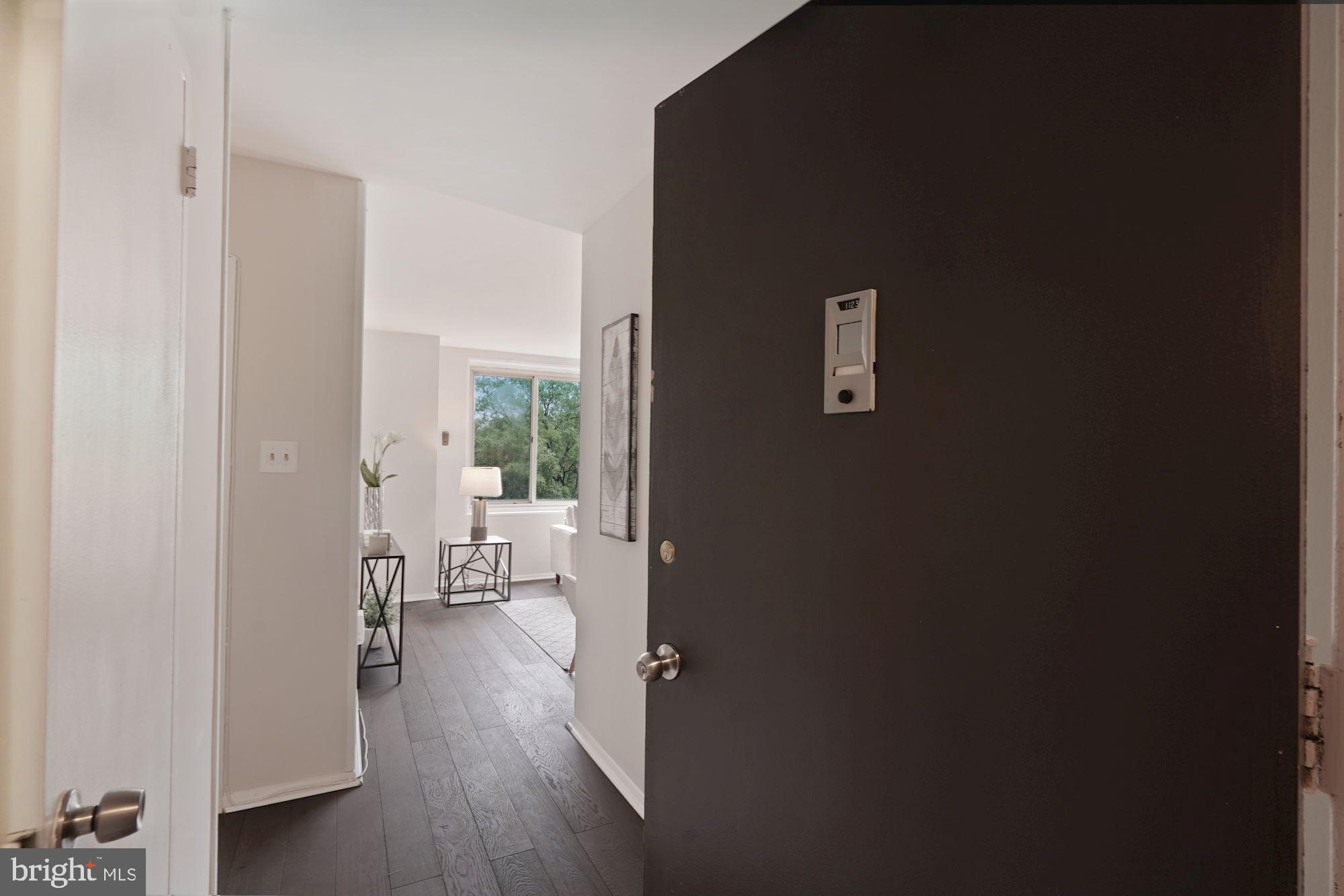 4000 Tunlaw Road Northwest, Unit 1123 Washington, DC 20007 - Photo 30 of 31 a view of a hallway with wooden floor and a livingroom with furniture