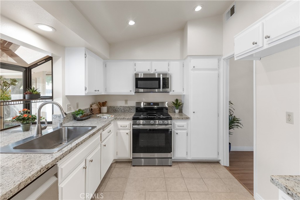 1157 West Orchard Street Rialto, CA 92376 - Photo 14 of 38 a kitchen with stainless steel appliances granite countertop a stove sink and refrigerator