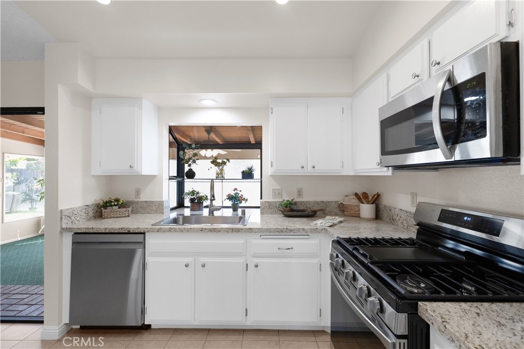 1157 West Orchard Street Rialto, CA 92376 - Photo 15 of 38 a kitchen with stainless steel appliances granite countertop white cabinets and window