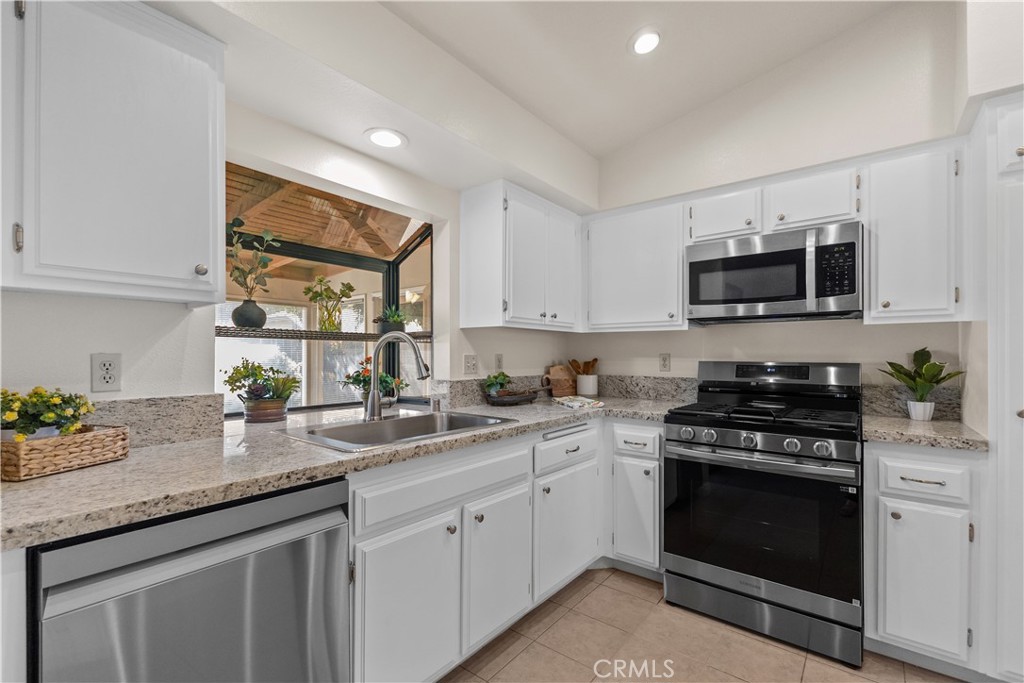 1157 West Orchard Street Rialto, CA 92376 - Photo 16 of 38 a kitchen with granite countertop a stove a sink and a microwave