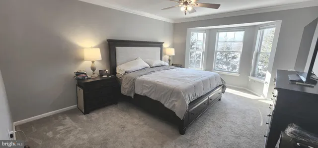 a bedroom with a bed lamp on desk and a window