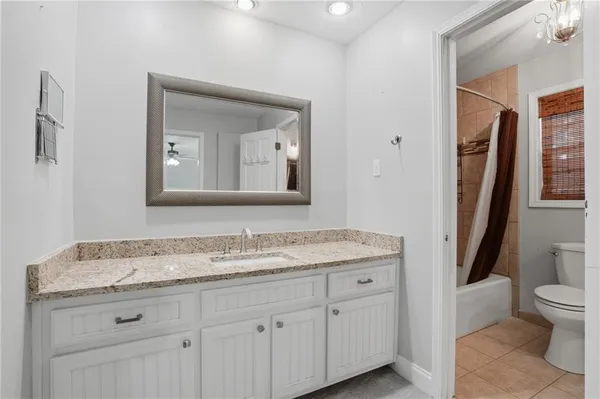 a bathroom with a granite countertop sink toilet and mirror