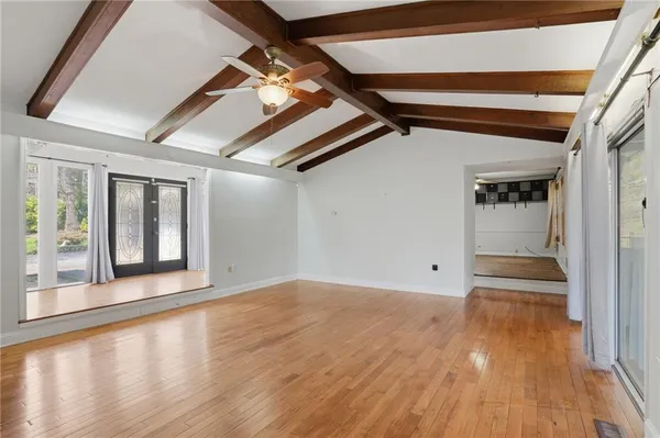 a view of an empty room with wooden floor and a window