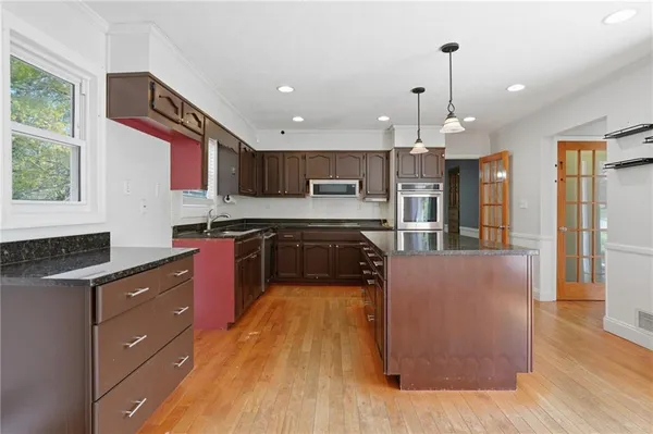 a large kitchen with stainless steel appliances granite countertop a stove a sink dishwasher and a refrigerator with wooden floor