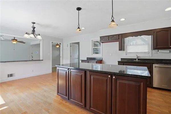 a kitchen with stainless steel appliances granite countertop a sink a stove and a wooden floors