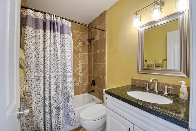a bathroom with a granite countertop sink toilet and shower